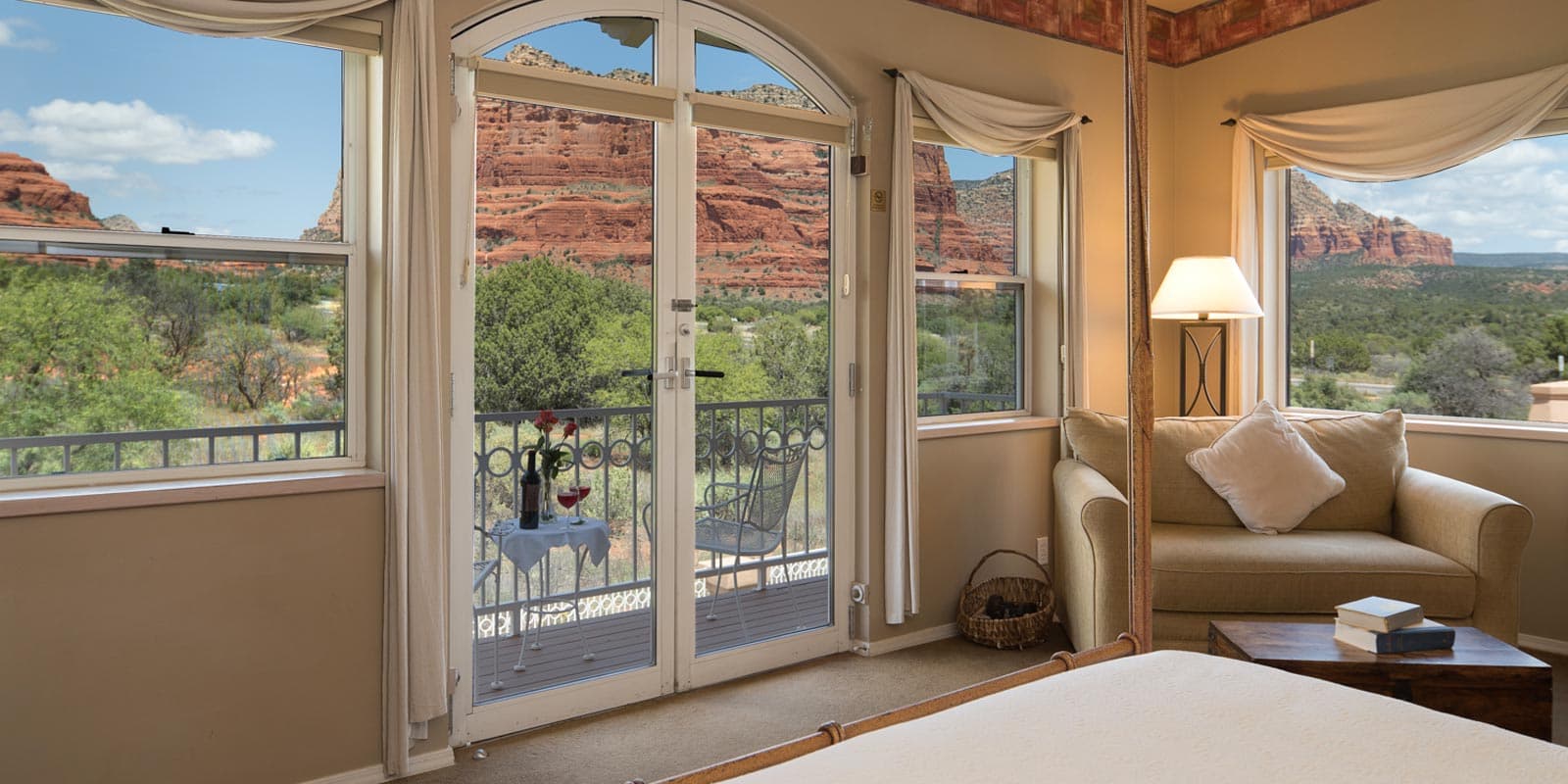 A cozy bedroom with large windows showcasing a stunning red rock landscape outside.